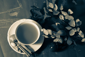 autumn tea drink in white elegance cup with waffers cinnamon and autumn leaves against white background