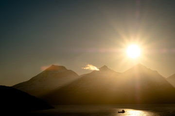 Obraz premium Scenic view of sunset over boat fishing in a dramatic landscape in Norway.