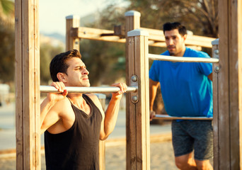 Naklejka premium Smiling adult men are doing pull-ups