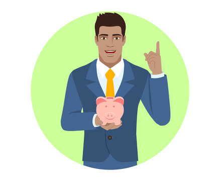 Businessman Holding A Piggy Bank And Pointing Up