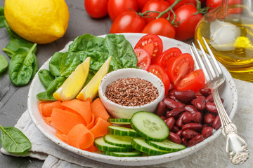 Vegetarian buddha bowl. Raw vegetables - tomatoes, cucumbers, beans, spinach, carrots, lemon and flax seed in a bowl. healthy, detox food concept. Selective focus