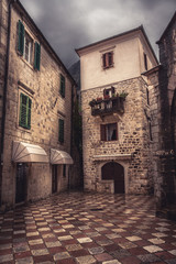 Fototapeta na wymiar Vintage medieval square with ancient stone pavers with medieval architecture in old european city Kotor in Montenegro 