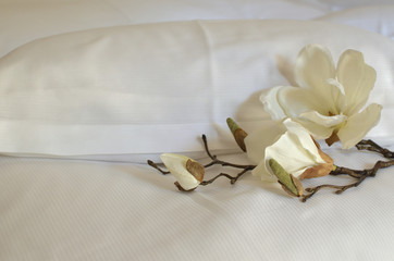 Two pillows in white cases and artificial orchids on them