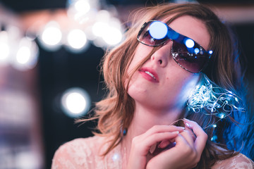 Attractive young caucasian woman poses with string lights with heavy bokeh