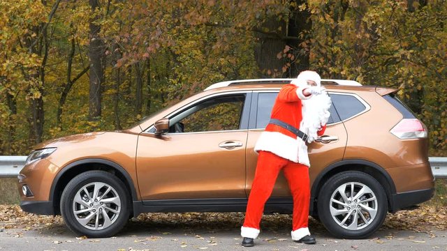 Santa Claus is dancing front of the car. Wood in the background. 50 fps