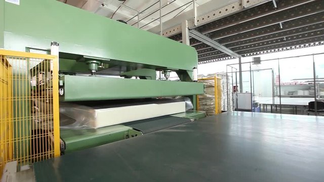 The mattress unit is supplied under a hydraulic press and compressed, hydraulic press compresses and wraps the mattress in cellophane, factory mattresses