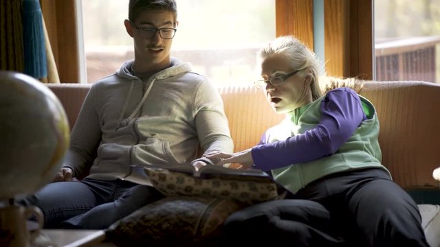 Homeschooling teenage boy and mother discuss art history with a globe of the world in front of them for reference in a relaxed living room atmosphere.