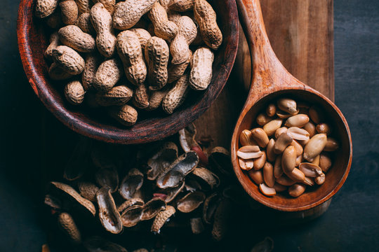 Peanuts in wooden cutting board on dark background