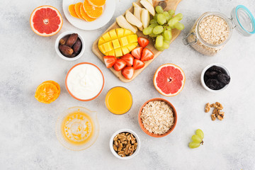 Above view of healthy breakfast with oats, variety of fruits, strawberries, mango, grapes, served on the white table, selective focus