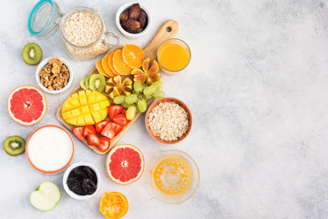 Healthy breakfast with oats, variety of fruits, strawberries, mango, grapes, figs, yogurt and nuts served on the white table, top view, copy space for text, selective focus