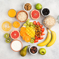 Top view of healthy breakfast with oats, variety of fruits, strawberries, mango, grapes, on the white table, square, selective focus