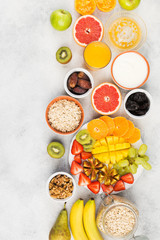 Top view of healthy breakfast with oats, variety of fruits, strawberries, mango, grapes, served on the white table, copy space for text, selective focus