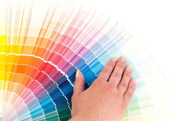 Person chooses a color in the palette for paint tinting. Colored catalog fan. The concept of design work