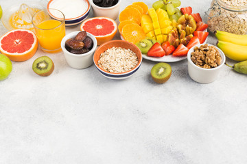 Top view of healthy breakfast with oats, variety of fruits, strawberries, mango, grapes, served on the white table, selective focus