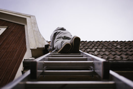 Man working on a roof on a ladder.
