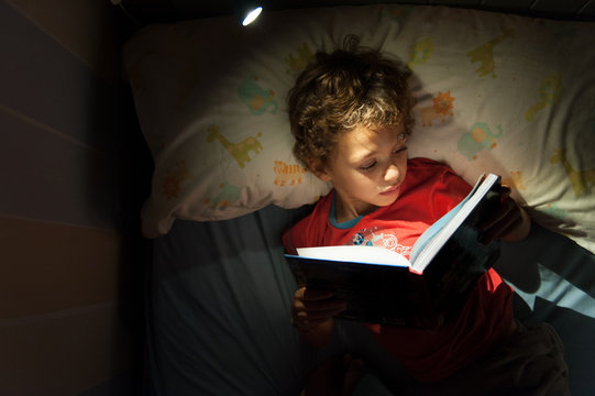 Child reading a book before going to sleep