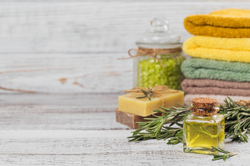 Natural cosmetic oil and natural handmade soap with rosemary on rustic wooden background.