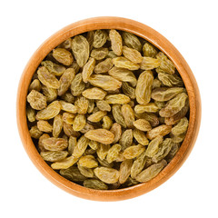 Green raisins in wooden bowl. Dried grapes. Vitis. Green seedless sultana variety from Asia. Eaten...