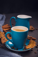 Blue cup of coffee with coffee beans and autumnal dry leaves