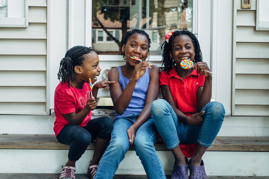 Three silly black girls with lollipops on steps