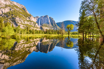 Fototapeta premium Yosemite National Park - Reflection in Merced River of Yosemite waterfall and beautiful mountain landscape, California, USA