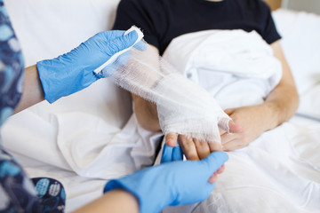 the nurse puts a bandage on a hand to a sick patient at home