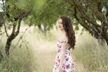 Fototapeta na wymiar Sweat young woman sitting in dry field wearing a floral short dress