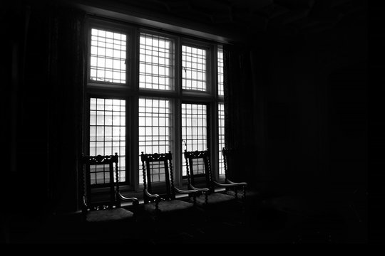 silhouette of chairs against a window in a dark room