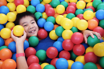 Fototapeta na wymiar Asian boy having fun in ball pit, indoor play