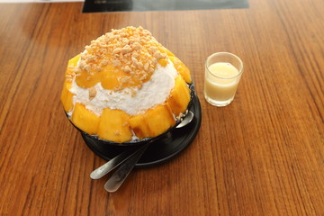 Korea Sweet Ice dessert famous with fruit colorful topping with milky sauce on wood table