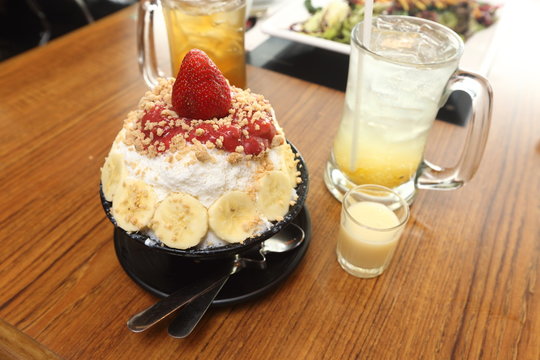 Korea Sweet Ice dessert famous with fruit colorful topping with milky sauce on wood table
