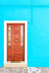 Brown door on blue wall of houses on the famous island Burano, Venice, Italy