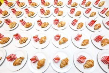 Pattern Arrangement of coffee break snack in complete set ready for paticipants after meeting, seminar, workshops, conference, catering on white fabric table, Croissant and strawberry cake