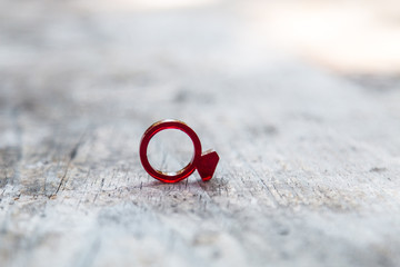 Modern red acrylic ring with diamond shape on distressed wooden table 