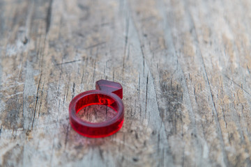 Modern red acrylic ring with diamond shape on distressed wooden table 