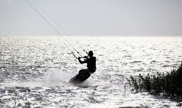 Kitesurfer in action, silhouetted against the bright water