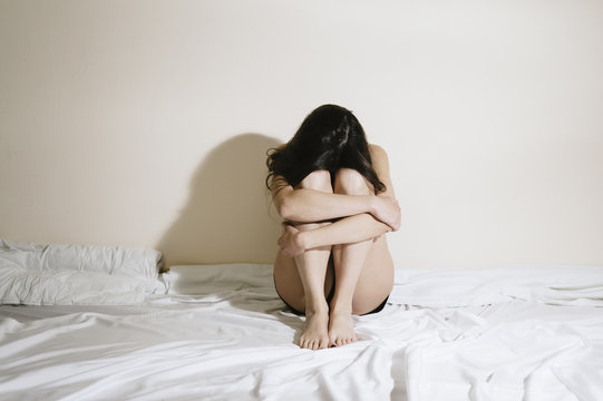 Sad young woman sitting on the bed