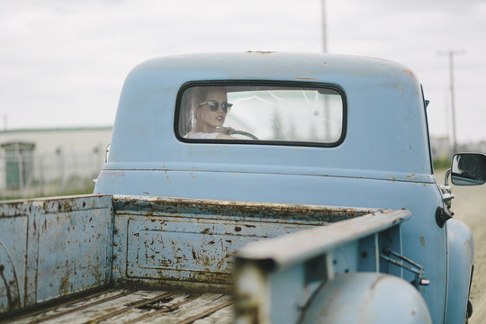 Blond girl driving an old pickup truck