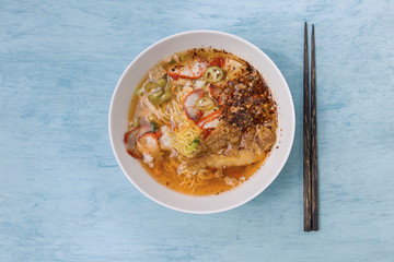 Spicy pork egg noodle soup on blue background