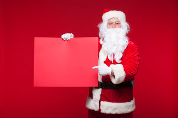 Santa Claus pointing in blank advertisement banner isolated on red background with copy space red leaf