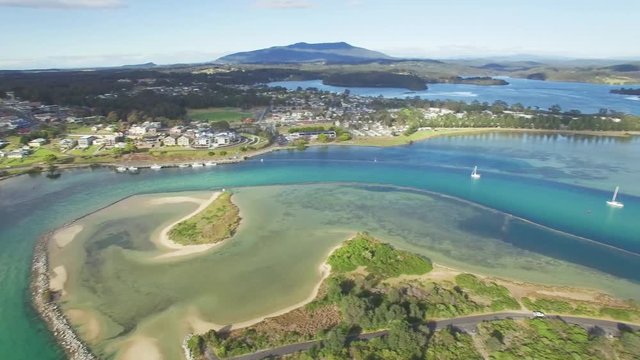 Aerial pan across beautiful ocean bay with shallow turquoise water and patches of sand. Magnificent vacation destination