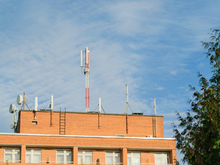 Fototapeta na wymiar Antennas mounted on the roof of a residential brick house.