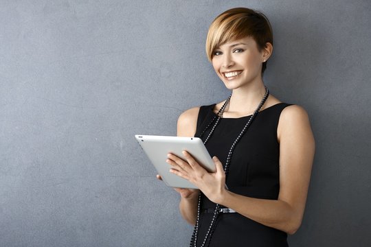 Elegant young woman using tablet leaning to wall
