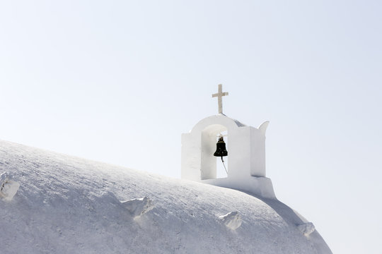 Roof and bell tower of a white church in Oia, Santorini