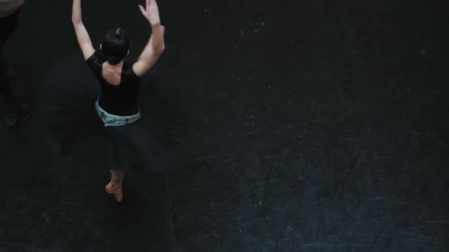 Young man practicing in classical ballet with young beautiful woman in black clothing in the gym. Minimalism interior, sensual dance. Training before the performance. Slow motion. Top view