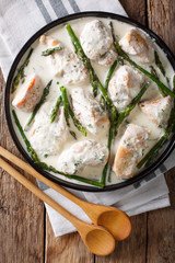 sliced chicken with baby asparagus in cream sauce close-up on the table. Vertical top view