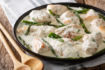 Stewed chicken with baby asparagus in a creamy sauce close-up. horizontal