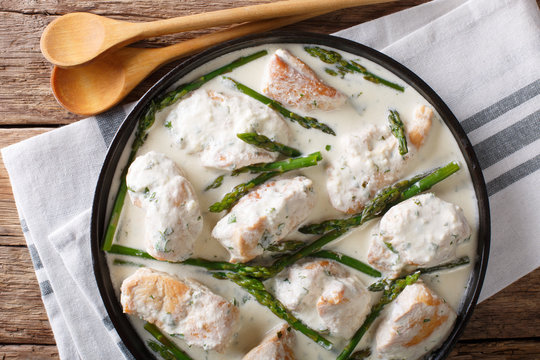 sliced chicken with baby asparagus in cream sauce close-up on the table. horizontal top view