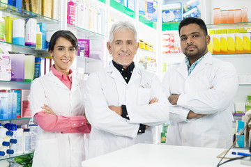 Multiethnic Pharmacists Standing Arms Crossed In Pharmacy