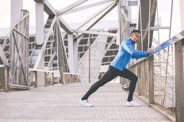 Sport man stretching on the urban background. Listening music to the smart phone.